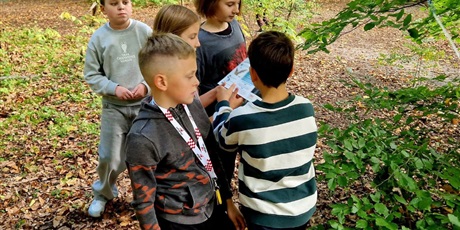 Powiększ grafikę: Uczniowie w czasie rozwiązywania zadań podczas gry terenowej